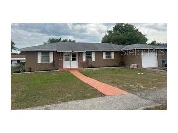 Single-story home featuring a white double-door entry, neutral siding, green grass, and a one-car garage at 7160 Lockwood St, Spring Hill, FL 34606