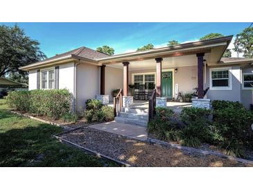 Charming home featuring a covered front porch, adorned with rocking chairs and stone-accented columns at 18101 Boy Scout Rd, Odessa, FL 33556