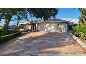 Inviting single-story home with a two-car garage and a well-maintained front yard with mature trees and stone-paved driveway at 891 Island Way, Clearwater Beach, FL 33767