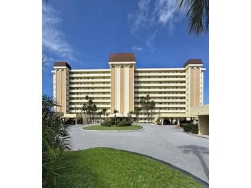 Spacious condominium with circular driveway, lush landscaping, and covered parking, set against a clear blue sky at 4750 Cove Cir # 502, St Petersburg, FL 33708