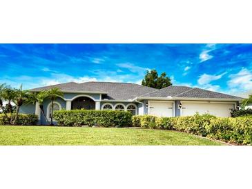 Charming one-story home with manicured lawn and a 2-car garage, framed by lush landscaping under a bright blue sky at 536 Boundary Blvd, Rotonda West, FL 33947