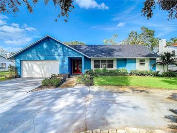 Ranch style home with blue exterior, white garage door, and well-manicured lawn at 8613 Beth Ct, Odessa, FL 33556
