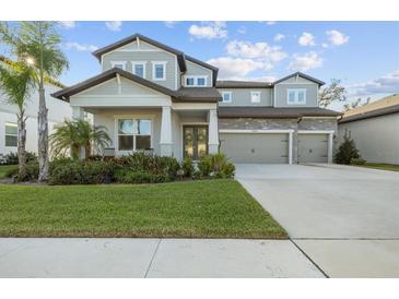 Two-story home with gray siding, three-car garage, and landscaped lawn at 11449 Owasee Trails Pl, Riverview, FL 33569