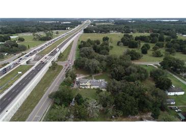 Expansive aerial view of a property with mature trees, a yellow home, and convenient highway access at 750 Charlie Taylor Rd, Plant City, FL 33566