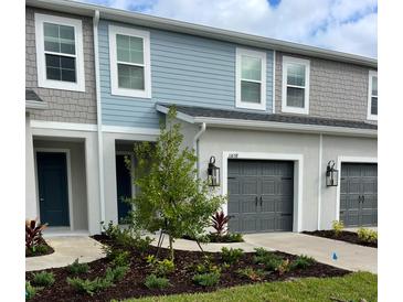 Charming two-story townhome featuring a gray garage door, and beautifully landscaped front yard at 11658 Bluestone Ct, Parrish, FL 34219