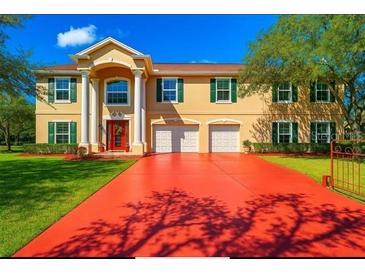 Inviting two-story home featuring a red driveway, well-maintained lawn, and traditional architecture with a bright red front door at 11175 Hyde St, Weeki Wachee, FL 34614