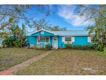 Charming blue cottage-style home with white trim, an American flag and a brick walkway to the front door at 1000 Michigan Blvd, Dunedin, FL 34698