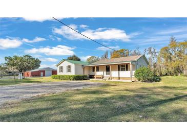 Charming single-story home with covered porch, lush lawn, and spacious red barn in the background at 7205 Anacapa Ln, Plant City, FL 33565