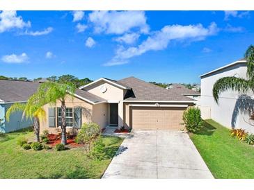 Charming one-story home featuring a well-manicured lawn, landscaping, and two-car garage on a sunny day at 15507 Caynor Ash Ln, Sun City Center, FL 33573