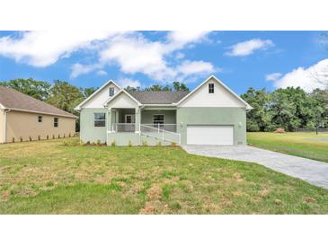 Charming single-story home featuring a well-manicured lawn and an attached two-car garage at 12484 Green Oak Ln, Dade City, FL 33525