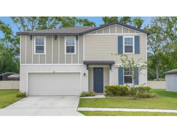 Charming two-story home features blue shutters and a well-maintained lawn and a two car garage at 203 Lovely Ct, Plant City, FL 33566