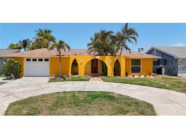 Charming yellow home with arched entryway, mature palms, and a circular driveway at 4921 Marlin Dr, New Port Richey, FL 34652