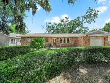 Charming single-story brick home with a well-manicured front yard and beautiful tree with hanging moss at 115 W Lee St, Plant City, FL 33563