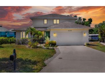 Two-story home featuring a lush landscaped yard, two car garage, and a beautiful sunset at 4116 4Th Ne Ave, Bradenton, FL 34208