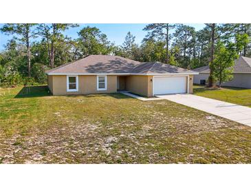 Charming single-story home featuring a spacious front yard, attached two-car garage, and neutral color palette at 12043 Centralia Rd, Weeki Wachee, FL 34614