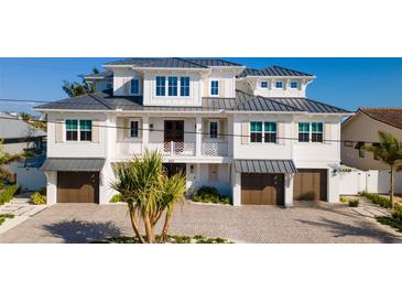 Stunning three-story coastal home with gray roof, white siding, and attached garages at 531 68Th St, Holmes Beach, FL 34217
