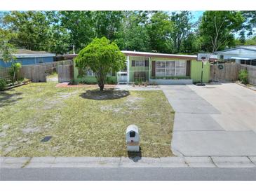 Charming single-story home with a well-manicured lawn, mature tree, and a basketball hoop on the driveway at 10804 N Leo St, Tampa, FL 33612