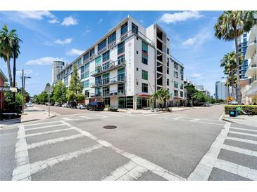 A modern, multi-story building with balconies and street views set against a blue sky with palm trees at 101 S 12Th St # 318, Tampa, FL 33602