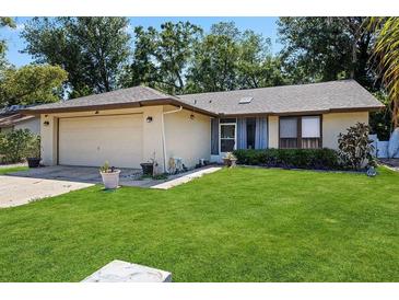 Charming single-story home with a well-manicured lawn and attached two-car garage at 13411 Whitby Rd, Hudson, FL 34667