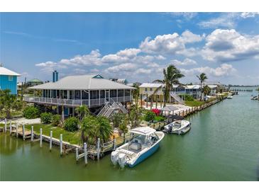 Coastal home featuring a metal roof, screened porch, boat dock and lush tropical landscaping at 9712 Little Gasparilla Is, Boca Grande, FL 33921