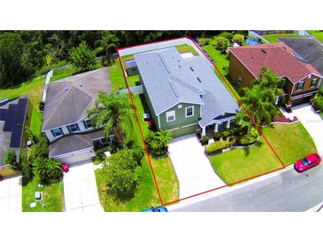 A beautiful green two-story home, surrounded by lush trees, manicured lawn, and a long concrete driveway at 2721 Walden Woods Dr, Plant City, FL 33566