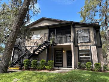 Two-story condo featuring neutral paint, black trim and railings, green bushes, and well-maintained landscaping at 4022 Tumble Wood Trl # 101, Tampa, FL 33613