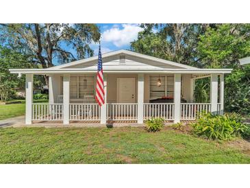 Charming home featuring a welcoming front porch adorned with an American flag at 4818 Huron St, Zephyrhills, FL 33541