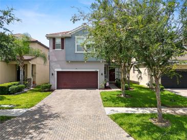 Charming two-story home featuring a paver driveway, manicured lawn, and mature trees at 1044 Oliveto Verdi Ct, Brandon, FL 33511