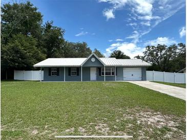 Charming single story home with a well-manicured lawn, white fence, and covered entryway at 37341 Rutledge Dr, Zephyrhills, FL 33541