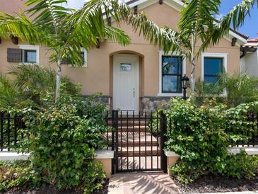 Inviting front door entry with landscaping and a black metal gate at 910 E Venice Ave, Venice, FL 34285