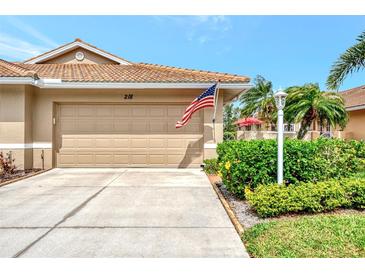 Two-car garage with manicured lawn and landscaping at 218 Auburn Woods Cir, Venice, FL 34292