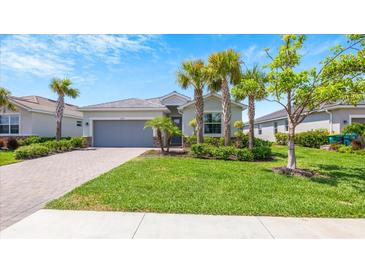 Charming one-story house with lush landscaping and a gray garage door at 15177 Spanish Point Dr, Port Charlotte, FL 33981