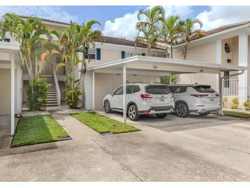 Exterior shot of the carport showing parking spaces, greenery and the condo's staircase in a sunny environment at 821 Montrose Dr # 103, Venice, FL 34293