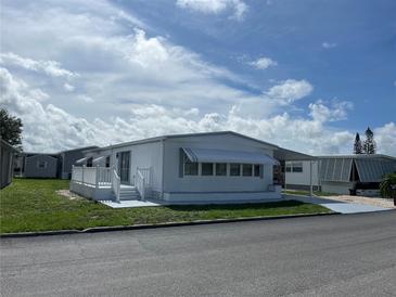 White single-wide manufactured home with carport and small deck at 923 Cortina Blvd, Venice, FL 34285
