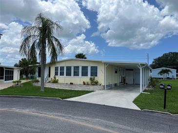 Yellow single-wide mobile home with carport and landscaping at 406 Trento, Venice, FL 34285
