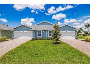 Two-unit building with light blue exterior, attached garages, and landscaping at 2129 Royal Tern Cir, Punta Gorda, FL 33983