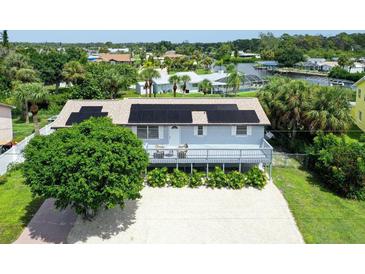 Aerial view of a canal-front home with solar panels and a large deck at 6 Cove Ln, Englewood, FL 34223