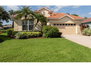 Tan house with tile roof, palm trees, and manicured lawn at 5221 Laurel Oak Ct, North Port, FL 34287