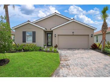 Tan one-story house with a two-car garage and landscaped yard at 376 Daylily Blvd, Nokomis, FL 34275