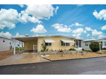 Cute yellow mobile home with carport and landscaping at 628 Cervina Dr, Venice, FL 34285