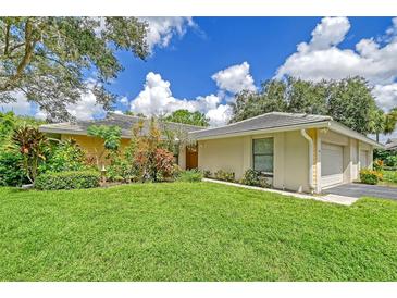 Tan house with a two-car garage and lush green lawn at 338 Pembroke Dr # 208, Venice, FL 34293