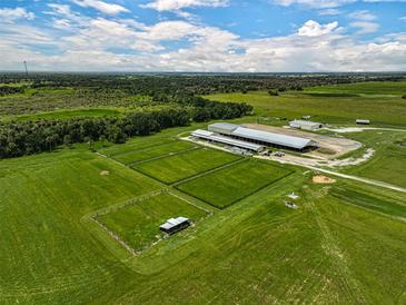 Aerial view of expansive equestrian property with multiple barns and paddocks at 27000 Harrison Rd, Sidell, FL 34266