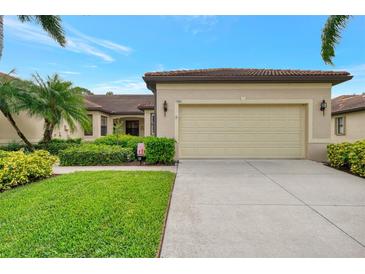 Front view of a tan house with a two-car garage and well-manicured lawn at 1780 Batello Dr, Venice, FL 34292