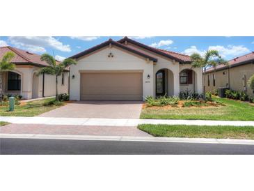 Single-story home with tan garage door and red tile roof at 24273 Spartina Dr, Venice, FL 34293