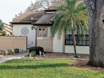 Tan exterior condo with mature landscaping and a walkway at 5650 Mashie Cir, North Port, FL 34287