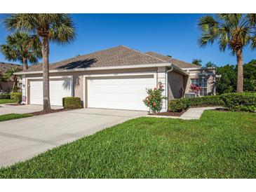 Tan Villa with three-car garage and lush landscaping at 4195 Fairway Pl, North Port, FL 34287