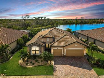 Stunning single-Gathering home featuring a three-car garage, tile roof, and paver driveway with lush landscaping at 13587 Vancanza Dr, Venice, FL 34293