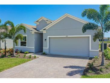 A gray house with a two-car garage and palm trees at 16851 Terrapin Key Dr, Port Charlotte, FL 33953