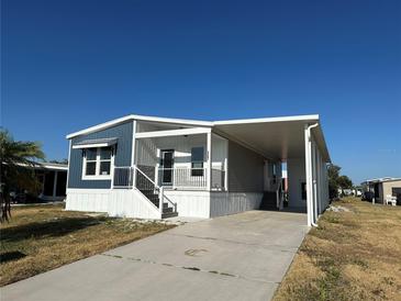 Charming manufactured home featuring a covered entrance, carport, and crisp blue and white paint at 127 Nautical Dr, North Port, FL 34287