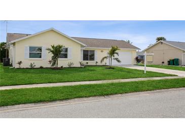 Newly constructed light-yellow home with a well-maintained lawn and attached garage at 13601 Isabell Ave, Port Charlotte, FL 33981